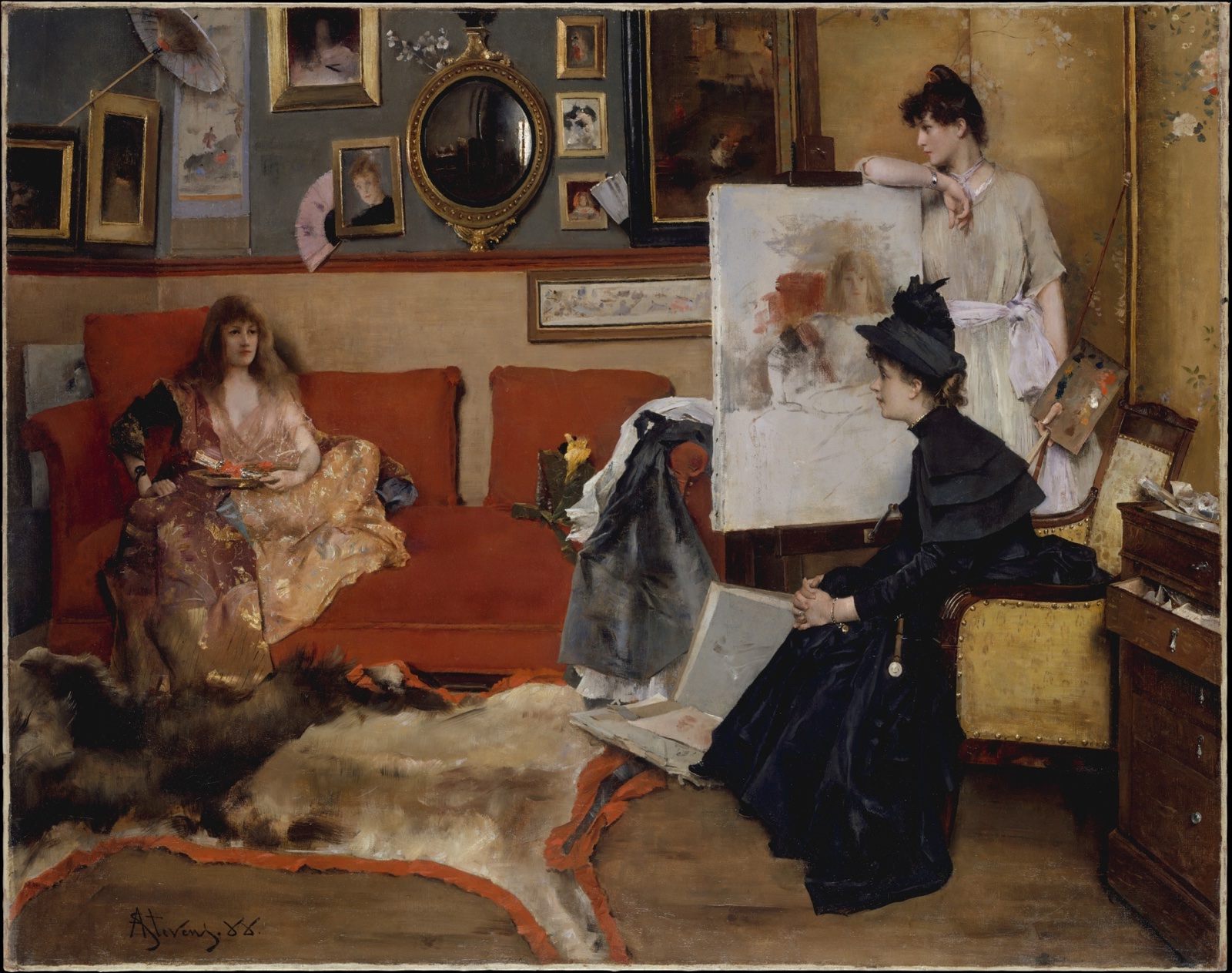 Un atelier élégant aux murs couverts de tableaux et d'objets : une femme en robe de chambre dorée allongée sur un canapé rouge, une femme debout près d'une toile en cours, et une femme en noir, chapeau sur la tête, assise face à la toile
