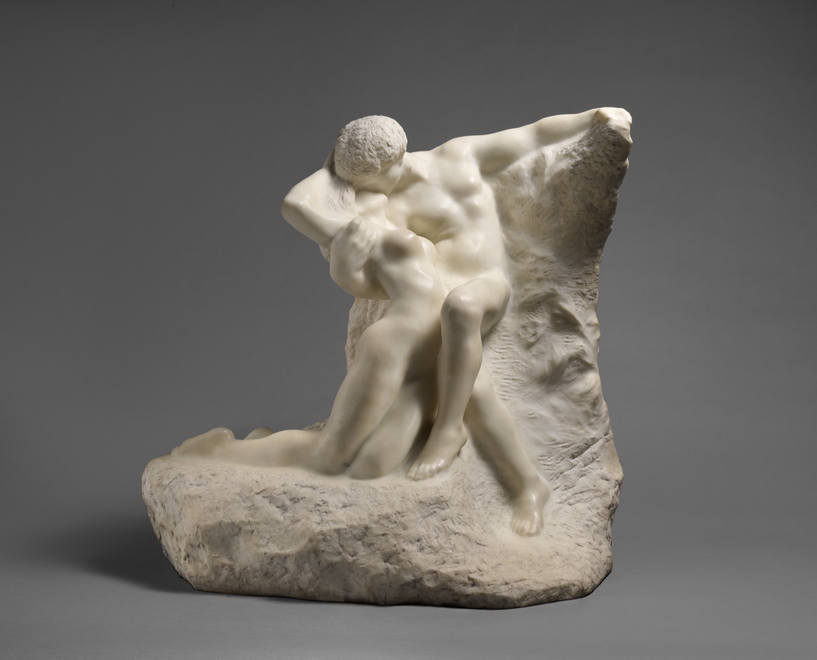 Sculpture de marbre blanc : un homme nu enlace et embrasse une jeune femme renversée contre lui, sur un bloc de pierre brute