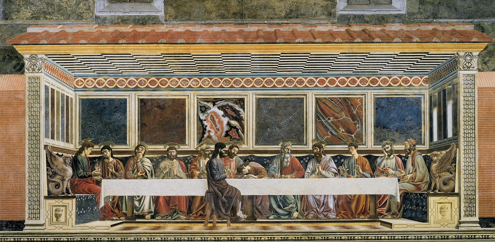 Fresque : le Christ et les apôtres attablés derrière une longue nappe blanche, Judas seul de l'autre côté de la table, devant des panneaux de marbre veiné