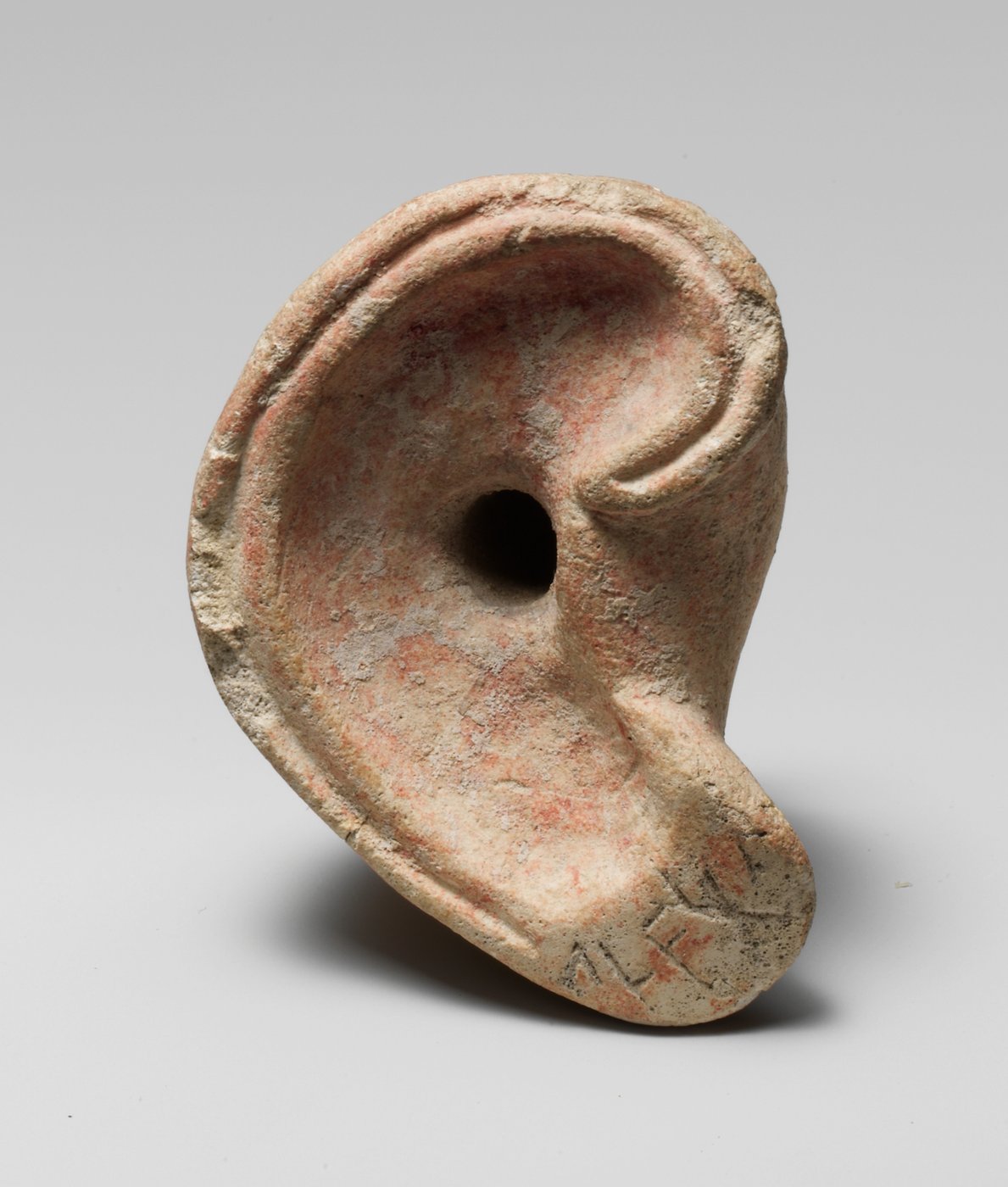 Petite oreille sculptée dans un calcaire clair, au pavillon creusé