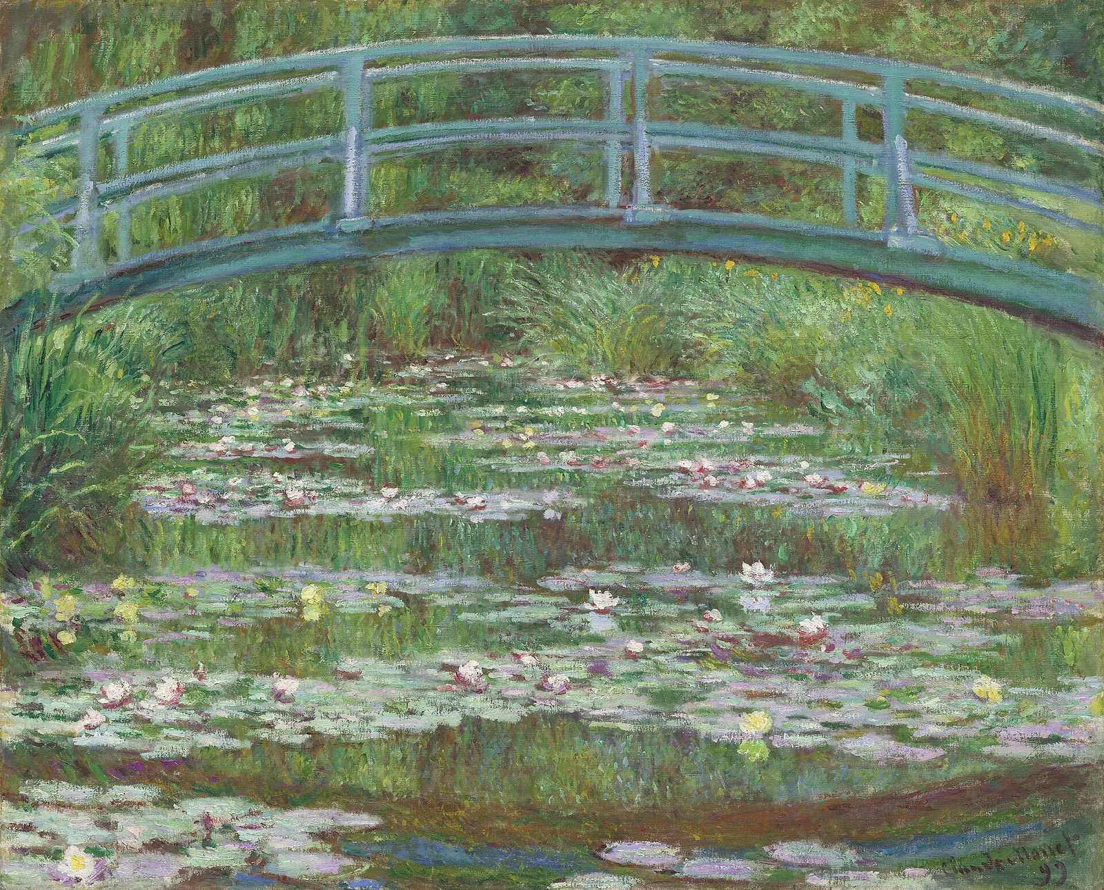 Une passerelle de bois vert en arc enjambe un bassin couvert de nymphéas blancs et roses, entouré de feuillages