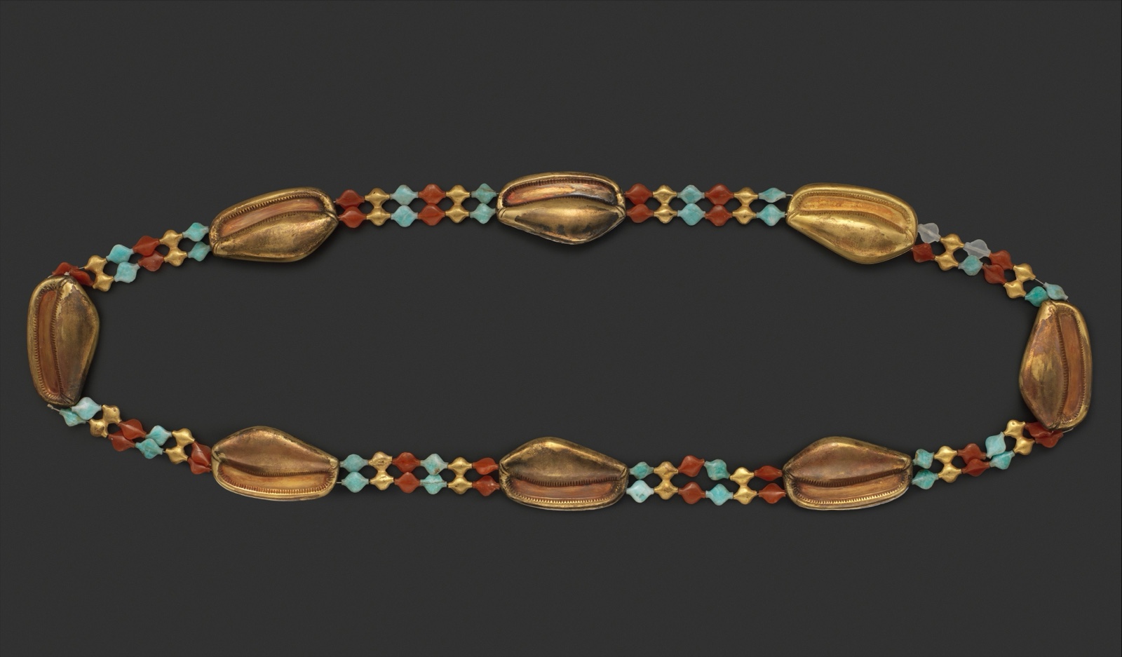 Ceinture faite de huit grands coquillages en or, reliés par des rangs de petites perles rouges, bleues et dorées